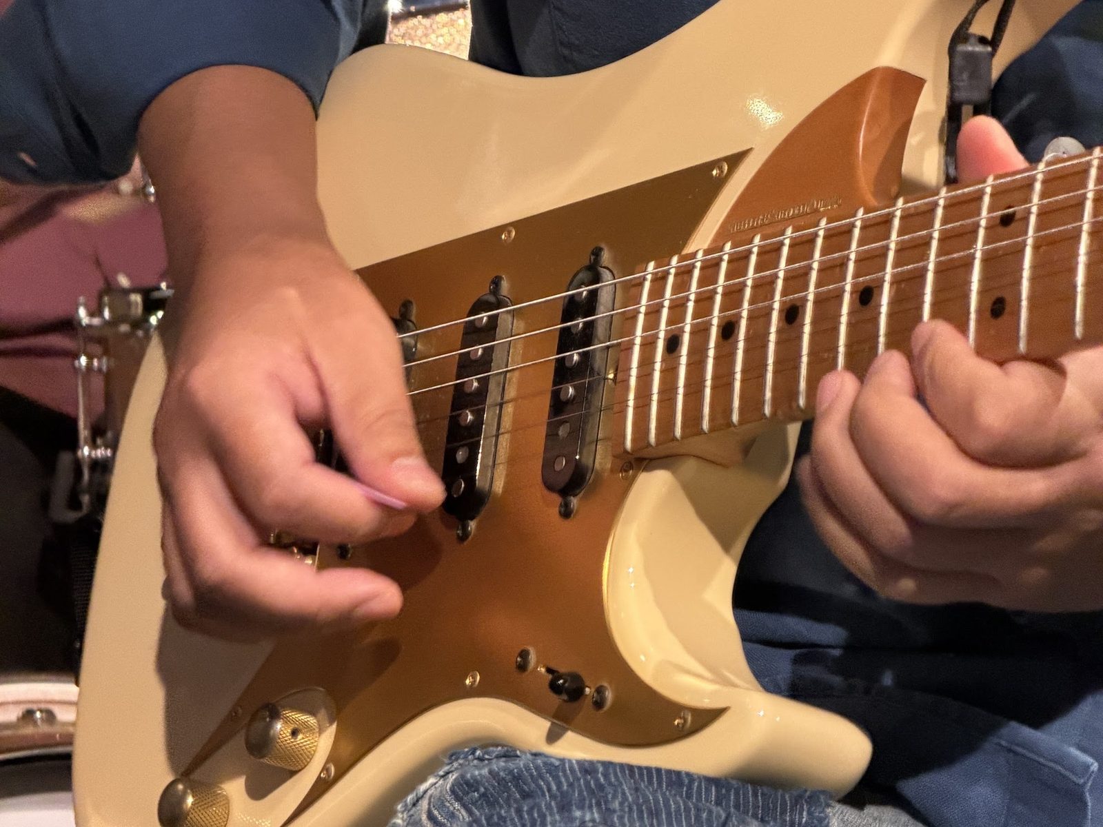 クリーム色のストラトタイプのギターを弾く、演奏中の手元のアップ
