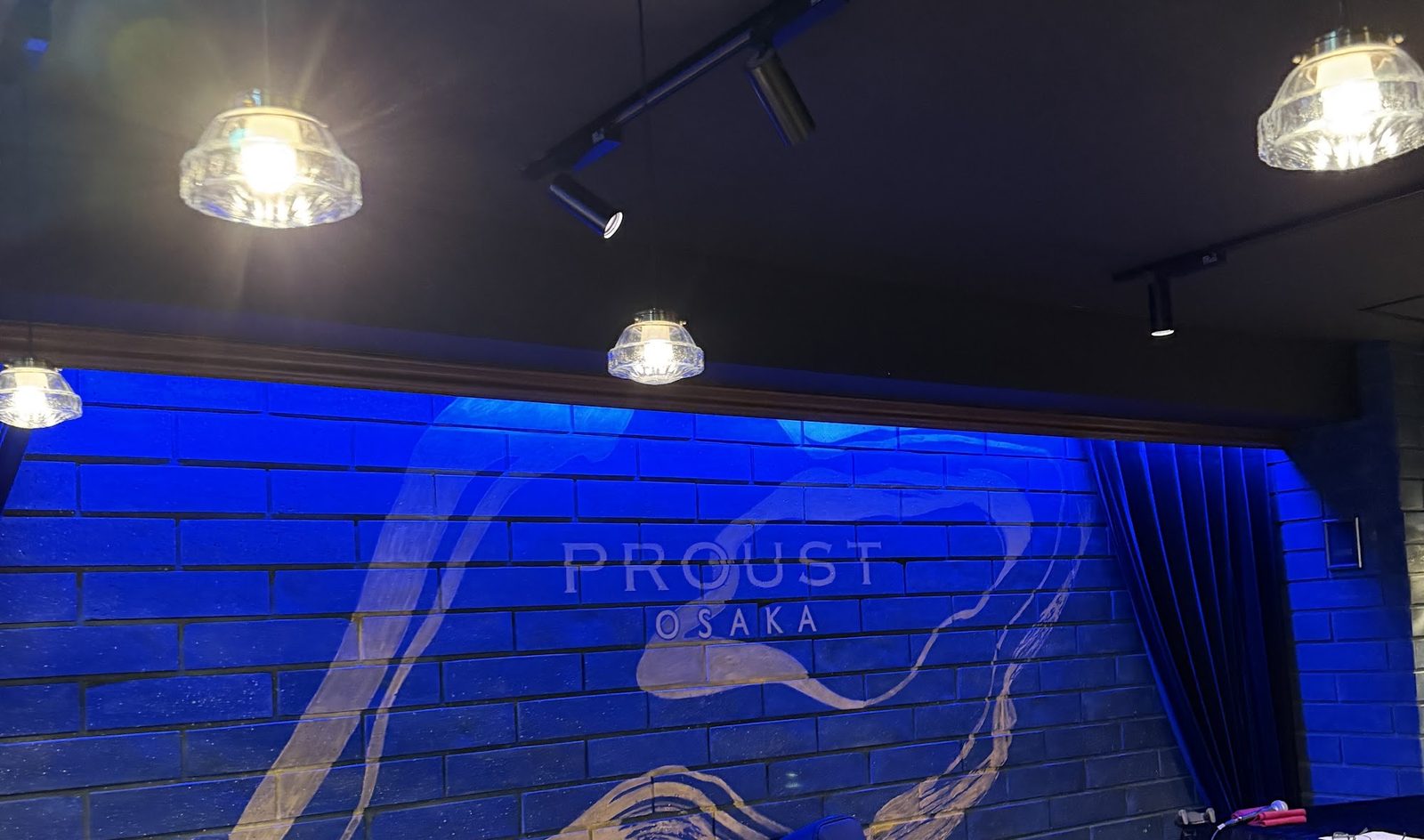発表会の会場になったPROUST OSAKA。青い照明に照らされたレンガの壁に店名のロゴ